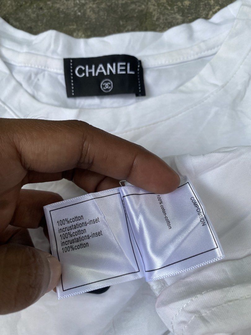 Chanel White Black Stripe Logo T-Shirt Medium (Category: Shirts) located in Abulug. Submitted by axeldot (Listing ID 1469653508, Image 3). Description: - Brand: Chanel - Color: White with black side stripes - Material: 100% cotton, Made in Italy - Size: Medium - Features: Black square logo patch on chest and matching inner collar brand tag - Flaws: Minor yellowish stains on lower front and some wear on the chest patch.