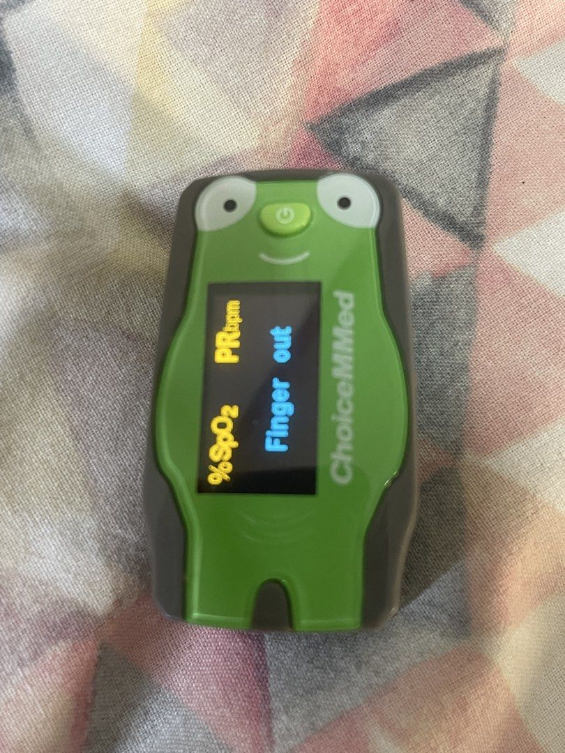 ChoiceMMed Pediatric Frog Pulse Oximeter (Category: Medical Supplies & Tools) located in Manila. Submitted by mdeclutter_mnl (Listing ID 1469617098, Image 2). Description: ChoiceMMed pediatric pulse oximeter shaped like a green frog. Finger-insert design with a digital screen displaying oxygen saturation percentage and pulse rate in beats per minute. Power button under the frog face. Includes protective plastic case. Original price: 1,300++ Rfs: 