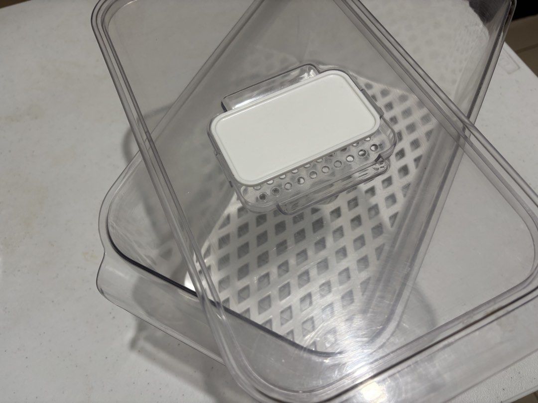 Clear Plastic Food Storage Container with Drain Tray (Category: Food Organization & Storage) located in Quezon City. Submitted by msuyo (Listing ID 1469579320, Image 2). Description: - Clear plastic food storage container with matching lid - Includes white grid drain tray to keep items elevated and dry - Features vented rectangular tab for airflow adjustment - Great size for organizing produce and fridge essentials - Clean and ready to use.