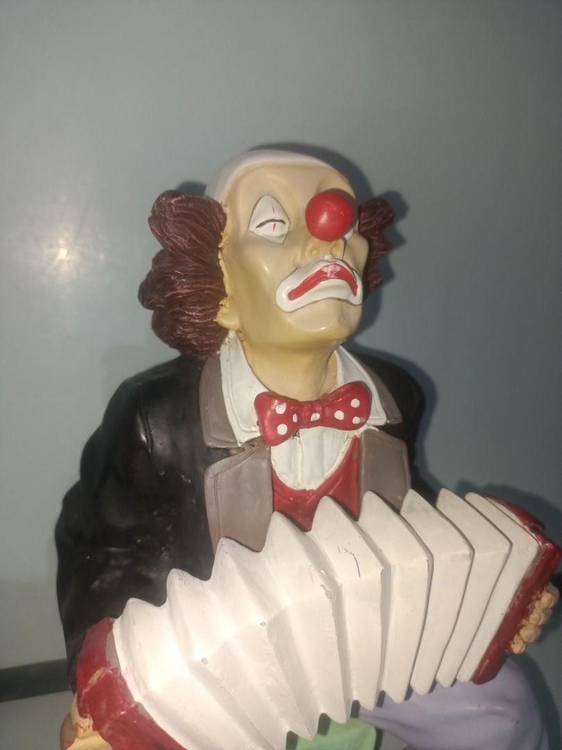 Clown playing accordion figurine (Category: Figurines & Statues) located in Munoz. Submitted by larryc1212 (Listing ID 1469678044, Image 2). Description: - Type: Clown statue playing an accordion - Size: Roughly 9.75 inches tall - Design: Detailed face paint, red nose, white makeup, and brown frizzy hair - Outfit: Black jacket, white shirt, polka dot bow tie, and light purple pants, seated on a green base - Condition: Good shelf decor - Ideal for