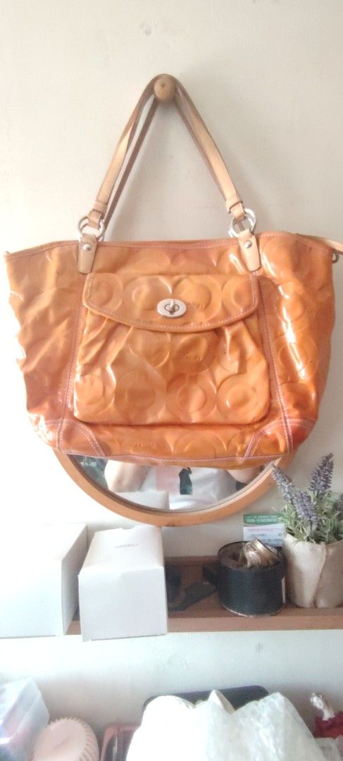Coach Patent Leather Orange Shoulder Bag (Category: Luxury Bags & Wallets) located in Manila. Submitted by lynnalec25 (Listing ID 1469672325, Image 1). Description: - Authentic Coach tote bag in a vibrant bright orange patent leather - Iconic embossed signature C pattern all over - Secure zip top closure and front flap pocket with classic turnlock - Comfortable double shoulder straps in matching leather - Spacious pink fabric-lined interior with 