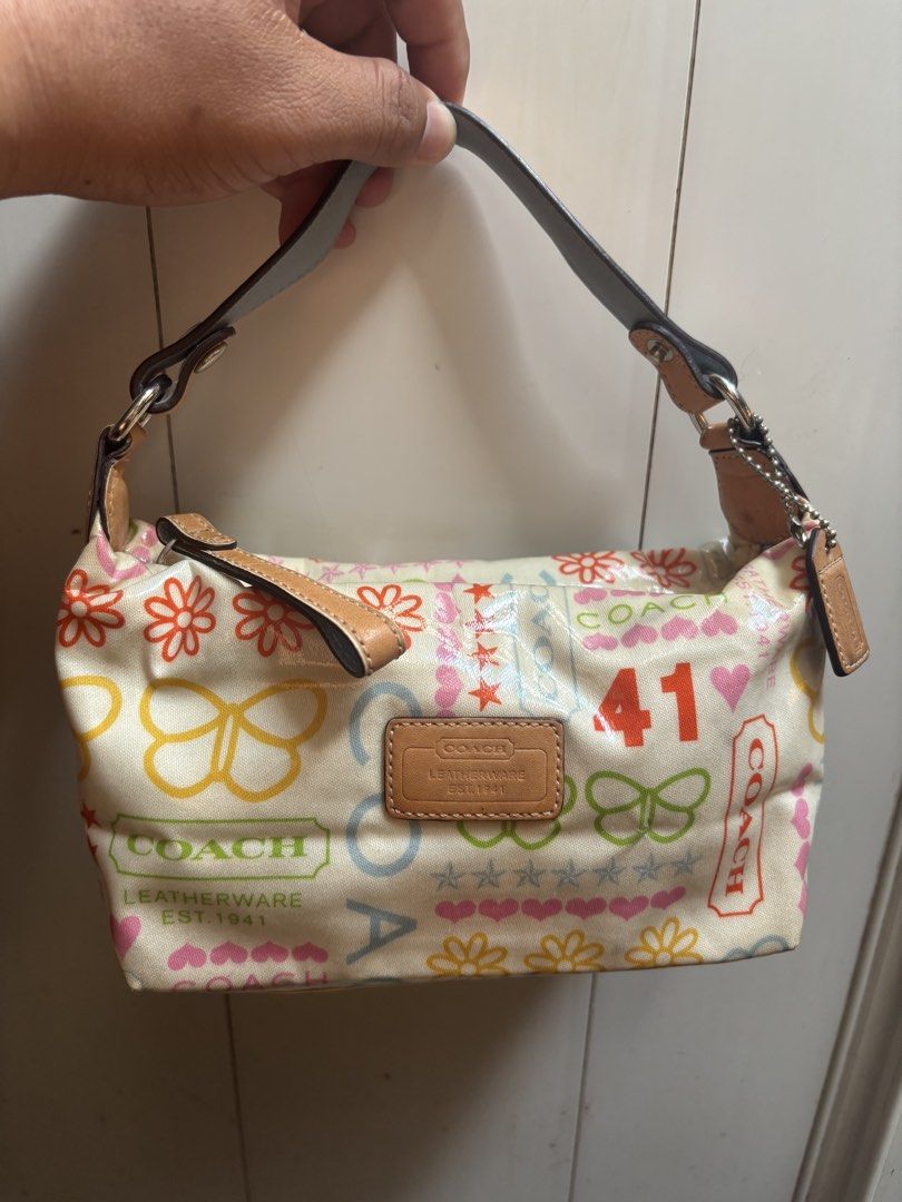 Coach Pop Signature Doodle Heritage Patchwork Tote Handbag (Category: Tote Bags) located in Subic. Submitted by thriftpoison (Listing ID 1469589817, Image 1). Description: - Authentic Coach Pop Signature Doodle Heritage Patchwork Small Shoulder Bag - Cream canvas base with playful retro Y2K graphics (flowers, butterflies, hearts, stars, '41') - Stylish tan leather trim and front embossed logo patch - Secure zipper closure with dark brown strap - 