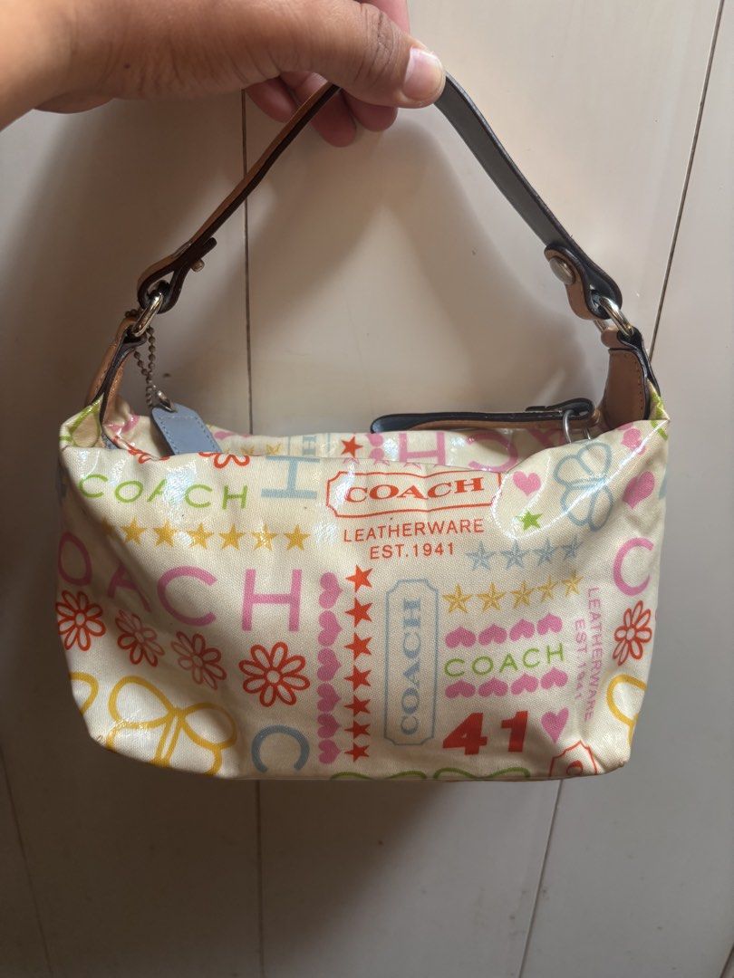 Coach Pop Signature Doodle Heritage Patchwork Tote Handbag (Category: Tote Bags) located in Subic. Submitted by thriftpoison (Listing ID 1469589817, Image 2). Description: - Authentic Coach Pop Signature Doodle Heritage Patchwork Small Shoulder Bag - Cream canvas base with playful retro Y2K graphics (flowers, butterflies, hearts, stars, '41') - Stylish tan leather trim and front embossed logo patch - Secure zipper closure with dark brown strap - 