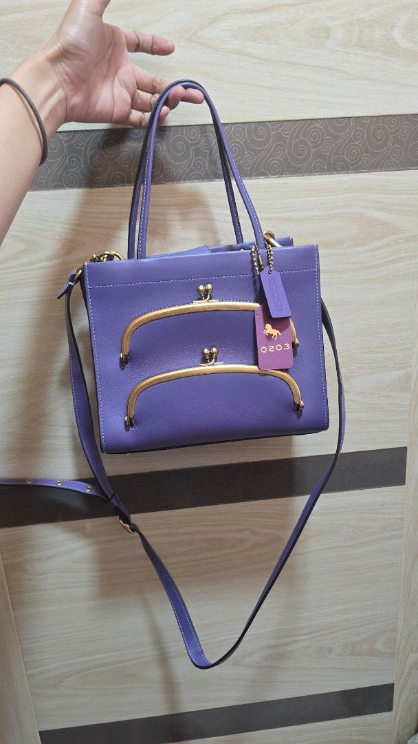 Coach Purple Leather Handbag with Gold Hardware (Category: Luxury Bags & Wallets) located in Quezon City. Submitted by mbpreloved65 (Listing ID 1469656776, Image 1). Description: - Brand: Coach - Material: Premium purple leather with brass-tone hardware - Design: Double gold clasp frames on the front - Extras: Matching purple leather hangtags, including one embossed with the horse and carriage logo and number 0203 - Carry options: Double top hand