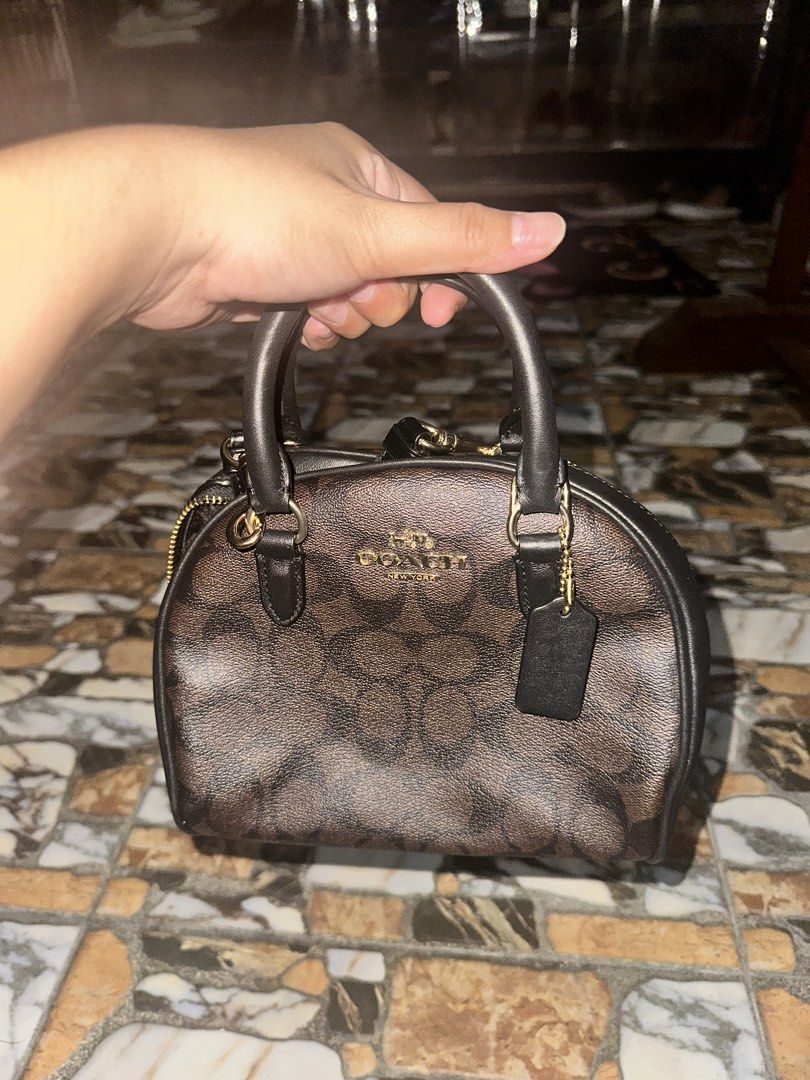 Coach Sydney Satchel Brown Black (Category: Luxury Bags & Wallets) located in Bugallon. Submitted by lavenderlane (Listing ID 1469669276, Image 1). Description: - Authentic Coach signature canvas mini satchel in classic brown and black - Elegant gold-tone hardware and signature leather hangtag - Versatile design with top handles and a detachable crossbody strap - Secure zip-top closure to keep your essentials safe - Clean interior featuring the o