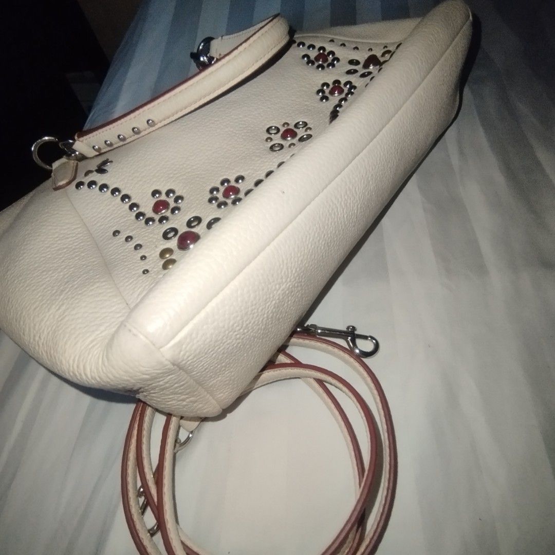 Coach White Leather Studded Handbag Shoulder Bag (Category: Cross-body Bags) located in Manila. Submitted by lene48 (Listing ID 1469649612, Image 3). Description: - Authentic Coach white pebbled leather bag - Silver-tone hardware with secure zipper closure - Unique front panel accented with metal studs and colorful stones - Dual top handles and a convenient detachable long strap - Classic Coach leather hangtag included - Clean back side with a ch