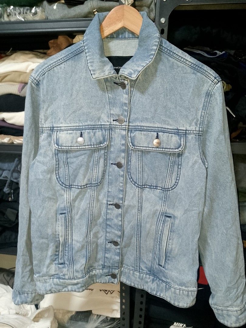 Coach x Mint + Serf Denim Jacket (Category: Coats, Jackets and Outerwear) located in Manila. Submitted by mjthrifted_second (Listing ID 1469635089, Image 1). Description: - Brand: Coach x Mint + Serf - Style: Light wash blue denim jacket with graffiti Coach logo on the back - Size: Small (Regular fit) -Dimes: 20/25 - Material: 100% cotton body with cow leather trim on the back hem patch - Features: Metal button closure, dual chest pockets, and si
