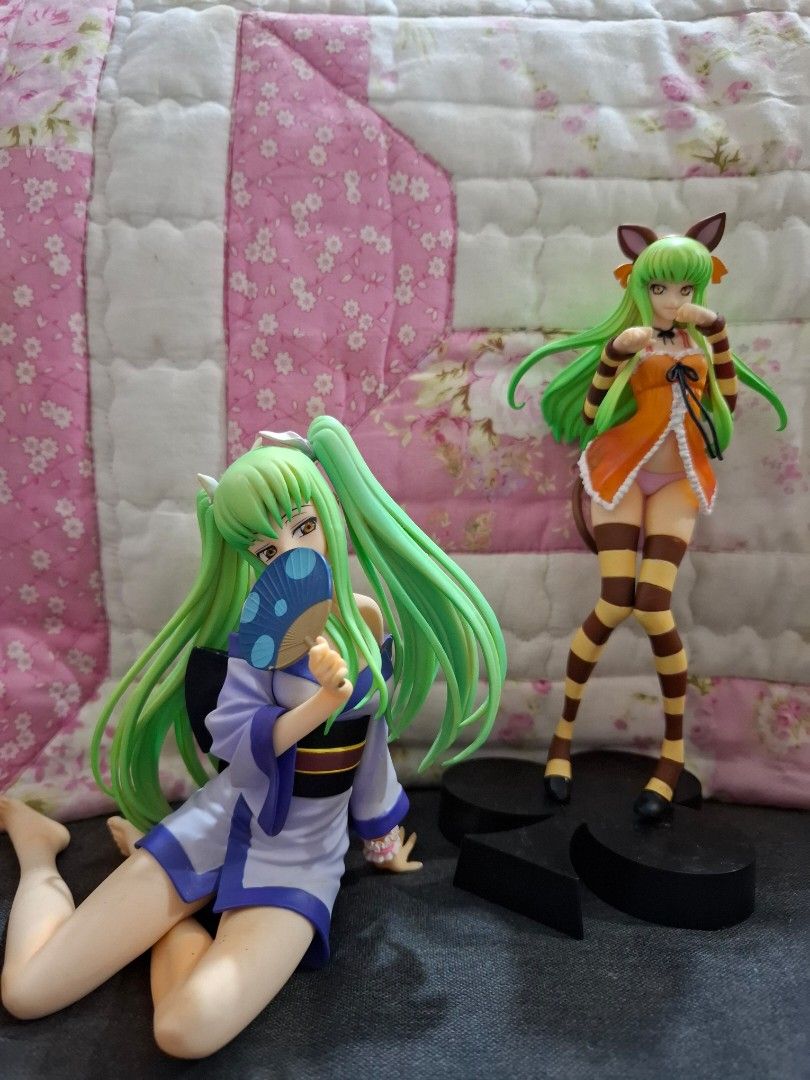Code Geass C.C. Figure Bundle (Category: Figurines & Statues) located in Orion. Submitted by timburtonfan (Listing ID 1469575450, Image 1). Description: - Authentic Code Geass C.C. Figure Set (2 figures) - Figure 1: Wears an orange top and striped stockings - Figure 2: Wears a white and blue outfit and holds a small blue fan - Signature long green hair on both figures - Includes a black display stand - Meet-ups and shipping available across the P