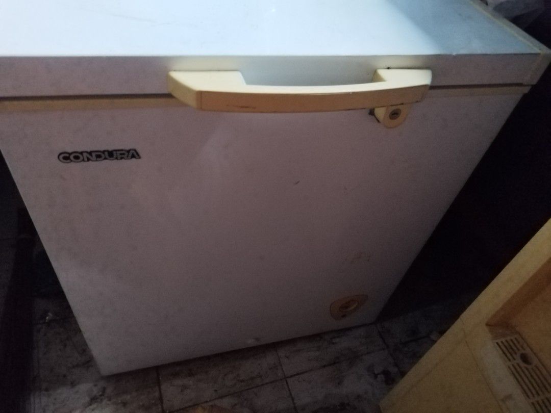 Condura Chest Freezer (Category: Refrigerators and Freezers) located in Makati City. Submitted by nerydevera (Listing ID 1469756667, Image 1). Description: - Brand/Model: Condura chest freezer - Condition: Fully working with minor signs of regular use - Exterior: White body with a yellowish handle and integrated lock - Interior: Deep storage space with a convenient removable wire storage basket - Perfect for: Extra food storage at home.