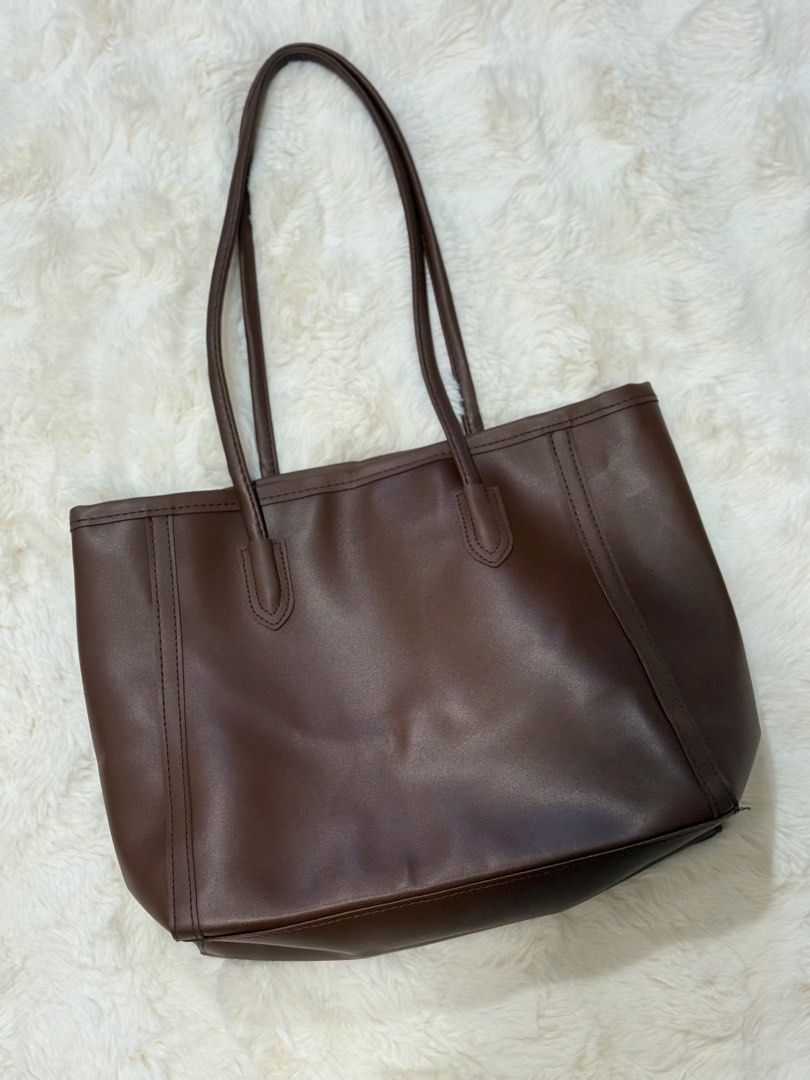 Dark Brown Leather Tote Bag Shoulder Bag (Category: Tote Bags) located in Manila. Submitted by preshyyyyy_ (Listing ID 1469746694, Image 1). Description: - Color: Solid dark brown (goes with everything) - Material: Premium leather with a clean finish - Design: Minimalist style with structured vertical front stitching - Straps: Long double shoulder straps for comfortable carrying - Capacity: Spacious interior, fits all daily essentials for work or