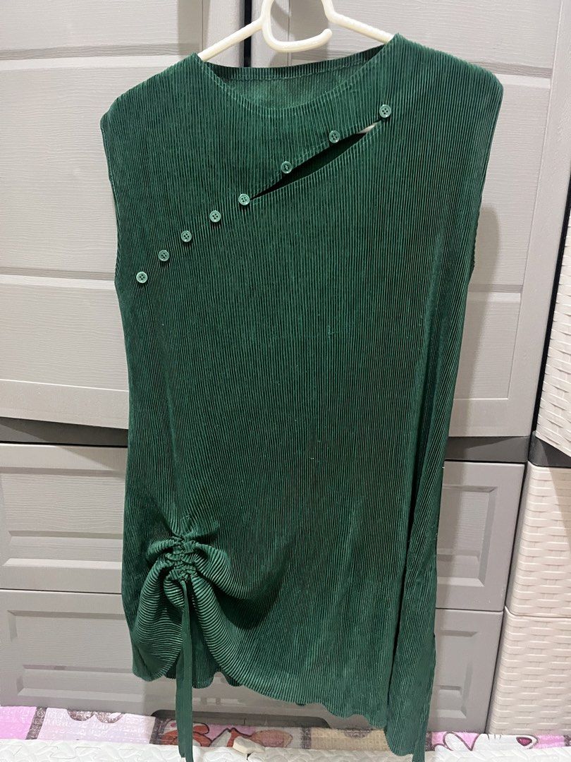Dark Green Pleated Sleeveless Top (Category: Sleeveless) located in Taguig. Submitted by notyoursam (Listing ID 1469690288, Image 1). Description: - Color: Dark green - Style: Sleeveless top with slip-on fit - Details: All-over vertical pleats, unique diagonal chest button, and slit hem at the bottom right - Fit: Adjustable drawstring ruching on the lower left side - Fabric: Lightweight and comfortable - Versatile: Great to pair with pants or ski