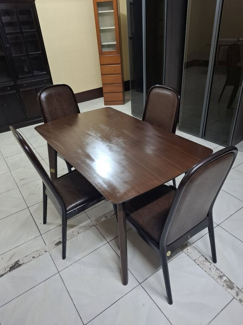 Dark Wood Dining Table with 4 Chairs (Category: Tables & Sets) located in Quezon City. Submitted by japandemanila (Listing ID 1469741934, Image 1). Description: - Rectangular dark brown wooden dining table with 4 matching chairs - Padded seats upholstered in durable dark brown faux leather - Sturdy frame with stylish angled legs - Space-saving design: chairs tuck neatly underneath the table - Ideal for everyday family meals or small apartments - 