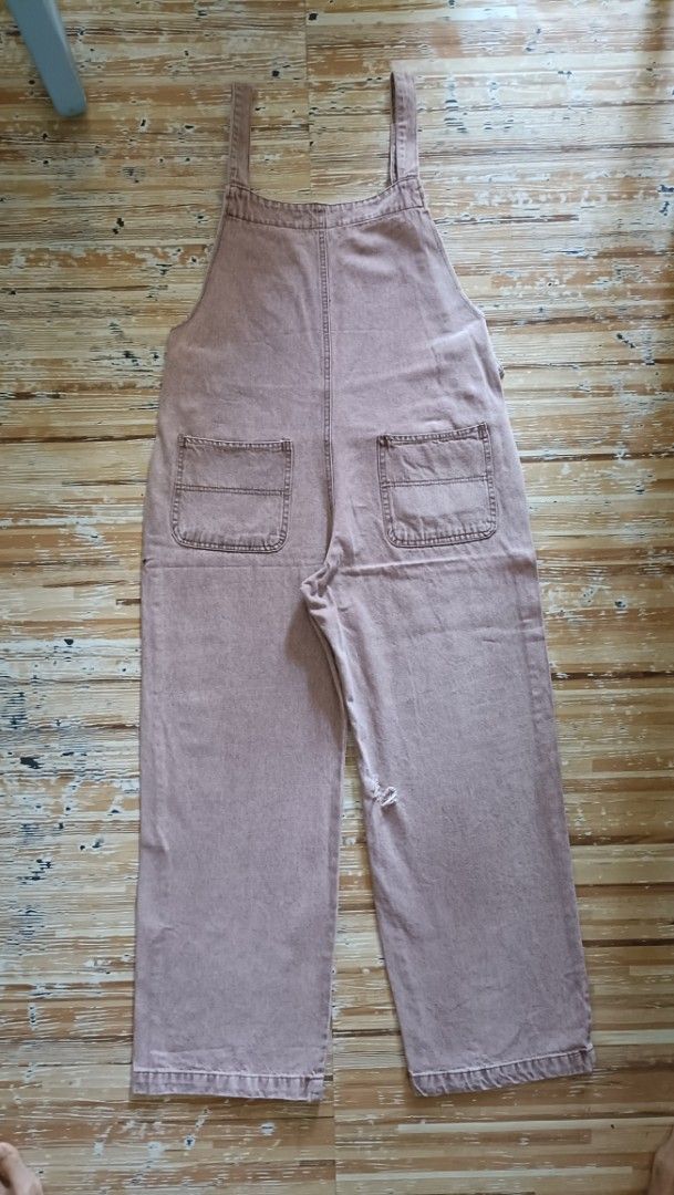 Denim Jumper Pants (Category: Jumpsuits) located in Dasmarinas. Submitted by kheiko086 (Listing ID 1469615689, Image 2). Description: W:34"L:37"Leg Hole:9.5" side zip/button adj strap hard denim EUC JNT Delivery - Style: Pink denim overalls with a relaxed wide-leg silhouette - Straps: Adjustable with metal O-rings and multiple eyelets - Pockets: Front bib pocket and two back patch pockets - Closure: Convenient side button closure - Fit: Comfortab