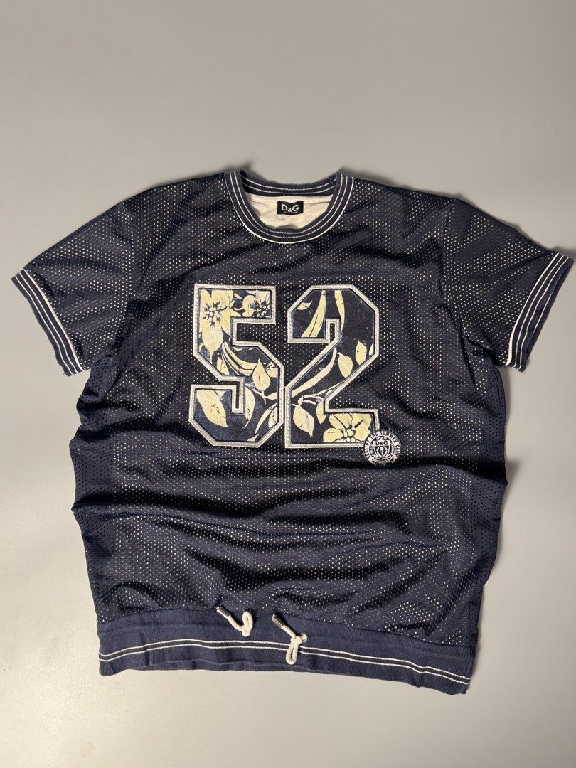 D&G Dolce & Gabbana Mesh Jersey 52 (Category: Tshirts & Polo Shirts ) located in San Pedro. Submitted by ygthriftshop (Listing ID 1469661030, Image 1). Description: - 21 x 27 - Brand: D&G Dolce & Gabbana - Style: Dark blue mesh jersey with white contrast ribbing on collar and cuffs - Graphic: Large number 52 on front filled with a stylish floral pattern - Fit/Size: Tagged Size L with an adjustable drawstring hem for a custom fit - Comfort: Featur