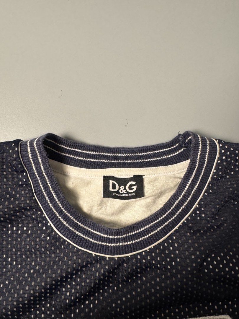 D&G Dolce & Gabbana Mesh Jersey 52 (Category: Tshirts & Polo Shirts ) located in San Pedro. Submitted by ygthriftshop (Listing ID 1469661030, Image 3). Description: - 21 x 27 - Brand: D&G Dolce & Gabbana - Style: Dark blue mesh jersey with white contrast ribbing on collar and cuffs - Graphic: Large number 52 on front filled with a stylish floral pattern - Fit/Size: Tagged Size L with an adjustable drawstring hem for a custom fit - Comfort: Featur