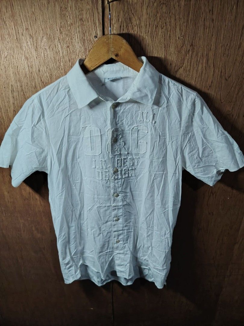 D&G Junior White Button-Up Shirt (Category: Shirts) located in Baguio. Submitted by tabuzomaria1422 (Listing ID 1469699983, Image 1). Description: - Brand: D&G Junior - Color: Classic White - Style: Short-sleeve button-up shirt - Design: Large embroidered D&G logo lettering on the chest - Details: Branded buttons down the front and collar neckline - Origin: Made in Turkey - Care: Wash and iron inside out (tag instructions included) Need Wash Only