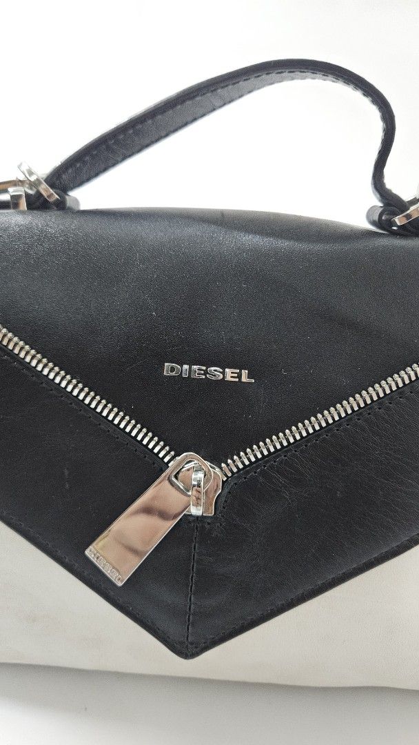 Diesel Black Leather Shoulder Bag (Category: Shoulder Bags) located in Alfonso. Submitted by jbcamet (Listing ID 1469703162, Image 3). Description: - Brand: Diesel - Material: Two-tone black and white leather - Design: Structured shape with a trendy slanted front zip pocket - Hardware: Silver-tone with a matching chain strap - Inclusions: Comes with the original Diesel dust bag - Condition: Good, with minor wear marks on the white leather body.