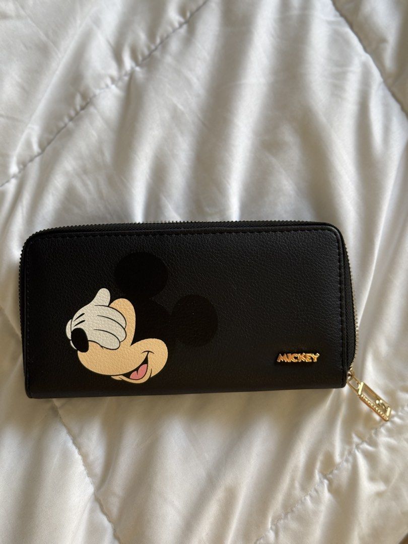 Disney Mickey Mouse Black Long Wallet (Category: Wallets & Card holders) located in Pasig City. Submitted by abbyrds (Listing ID 1469645157, Image 1). Description: - Disney Mickey Mouse zip-around wallet - Material: Premium black polyurethane with chic gold-tone hardware - Cute Mickey-shaped metal zipper pull detail - Interior organization: Multiple card slots, bill compartments, and a secure zippered coin pocket - Condition: Brand new with origi