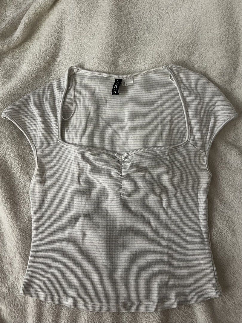 Divided by H&M White Striped Square Neck Ribbed Top (Category: Sleeveless) located in San Leonardo. Submitted by hmmmhehe (Listing ID 1469639498, Image 1). Description: - Brand: Divided by H&M - Design: White with blue stripes, square neckline, and short cap sleeves - Details: Center ruched chest with a tiny white satin bow - Material: Soft and stretchy - Size: L (fits M but a bit big on the bust) - Condition: Great for casual, chic outfits.