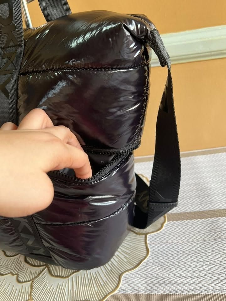 DKNY Black Puffer Tote Bag with Shoulder Strap (Category: Tote Bags) located in Quezon City. Submitted by bellafashion08 (Listing ID 1469731288, Image 2). Description: - Brand: DKNY Dimension: - Height = 12 in. - Length = 14 in. * From U.S * Nice in actual - Material: 100% Nylon with PU trim (Mfg Date: August 2021) - Design: Puffy glossy finish with branded black webbed straps - Storage: Spacious interior with dark patterned lining and front zipp