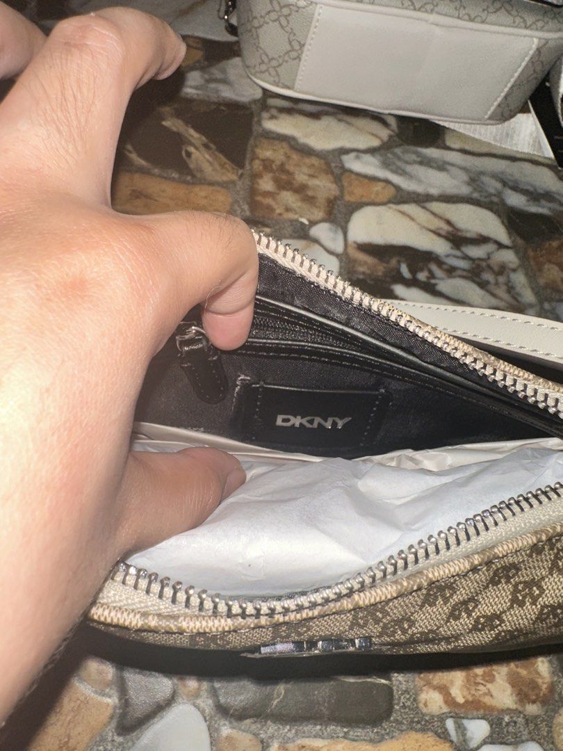 DKNY Monogram Shoulder Bag (Category: Luxury Bags & Wallets) located in Bugallon. Submitted by lavenderlane (Listing ID 1469669275, Image 3). Description: - Brand: DKNY - Style: Monogram shoulder bag - Color: Brown with white trim - Hardware: Silver-tone with zip top closure - Interior: Black fabric lining with a zippered pocket and brand patch - Condition: Brand new with original hang tag attached - Size: Compact, ideal for daily essentials.