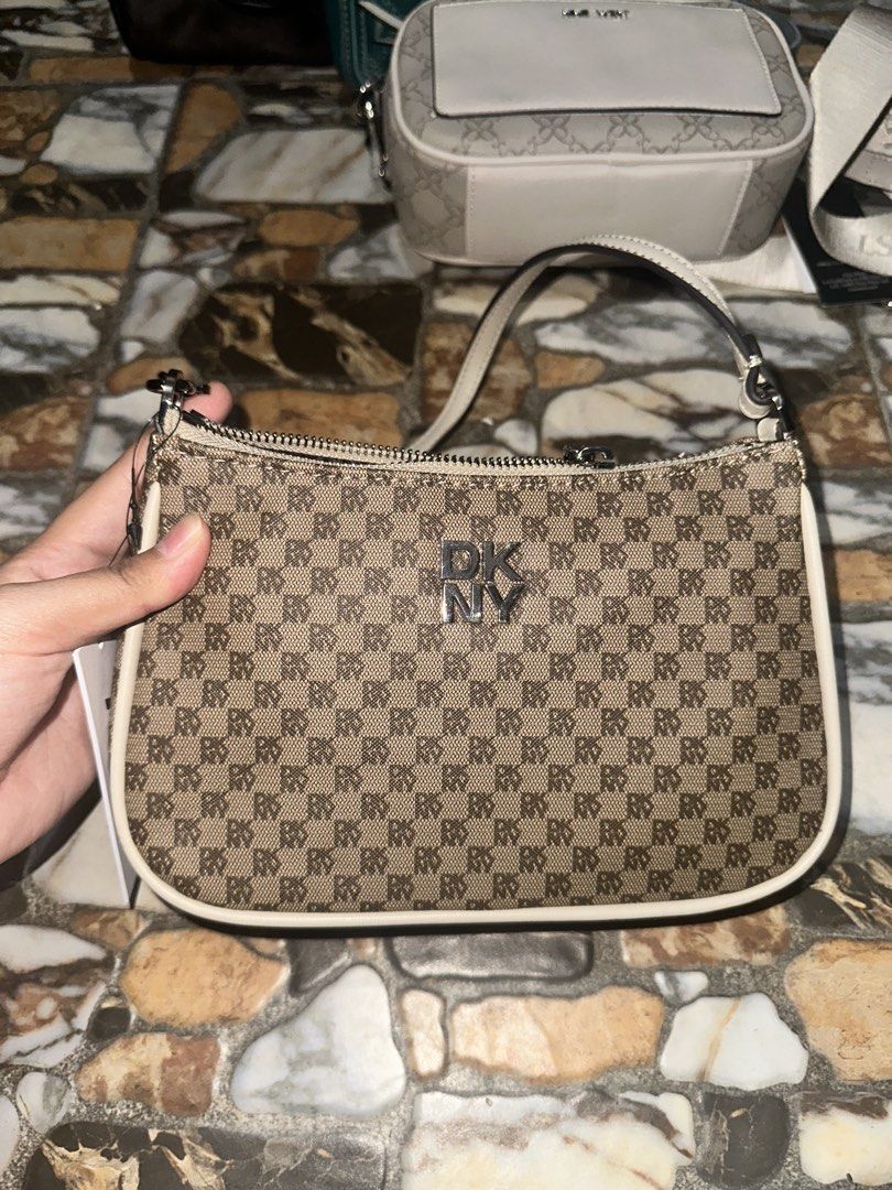 DKNY Monogram Shoulder Bag (Category: Luxury Bags & Wallets) located in Bugallon. Submitted by lavenderlane (Listing ID 1469669275, Image 1). Description: - Brand: DKNY - Style: Monogram shoulder bag - Color: Brown with white trim - Hardware: Silver-tone with zip top closure - Interior: Black fabric lining with a zippered pocket and brand patch - Condition: Brand new with original hang tag attached - Size: Compact, ideal for daily essentials.