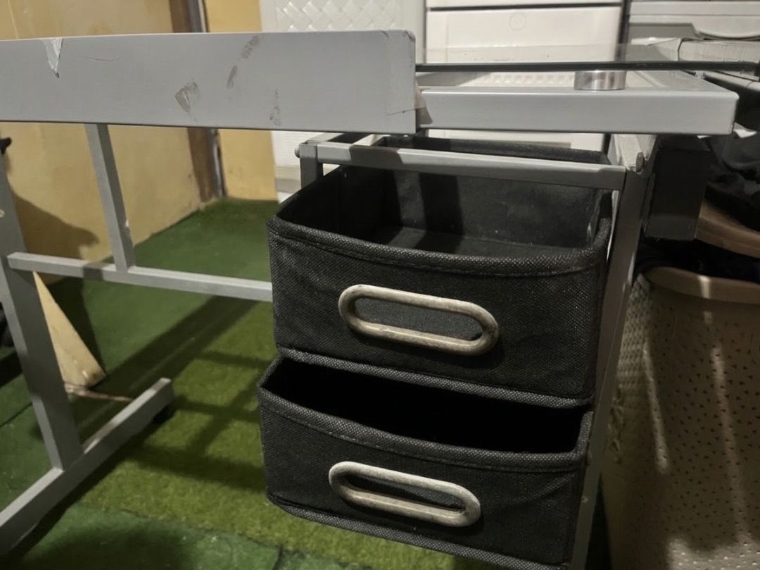 Drafting Glass Table with Extra Side Table Drawers (Category: Tables & Sets) located in Caloocan City. Submitted by elle.23 (Listing ID 1469691732, Image 3). Description: - Adjustable glass top drafting table - Durable grey steel frame with wheels for easy mobility - Includes 2 black fabric storage drawers - Features side storage trays with pen slots and cup holders - Dimensions: approx. 40.9" (W) x 23.6" (D) - Perfect workstation for architects,