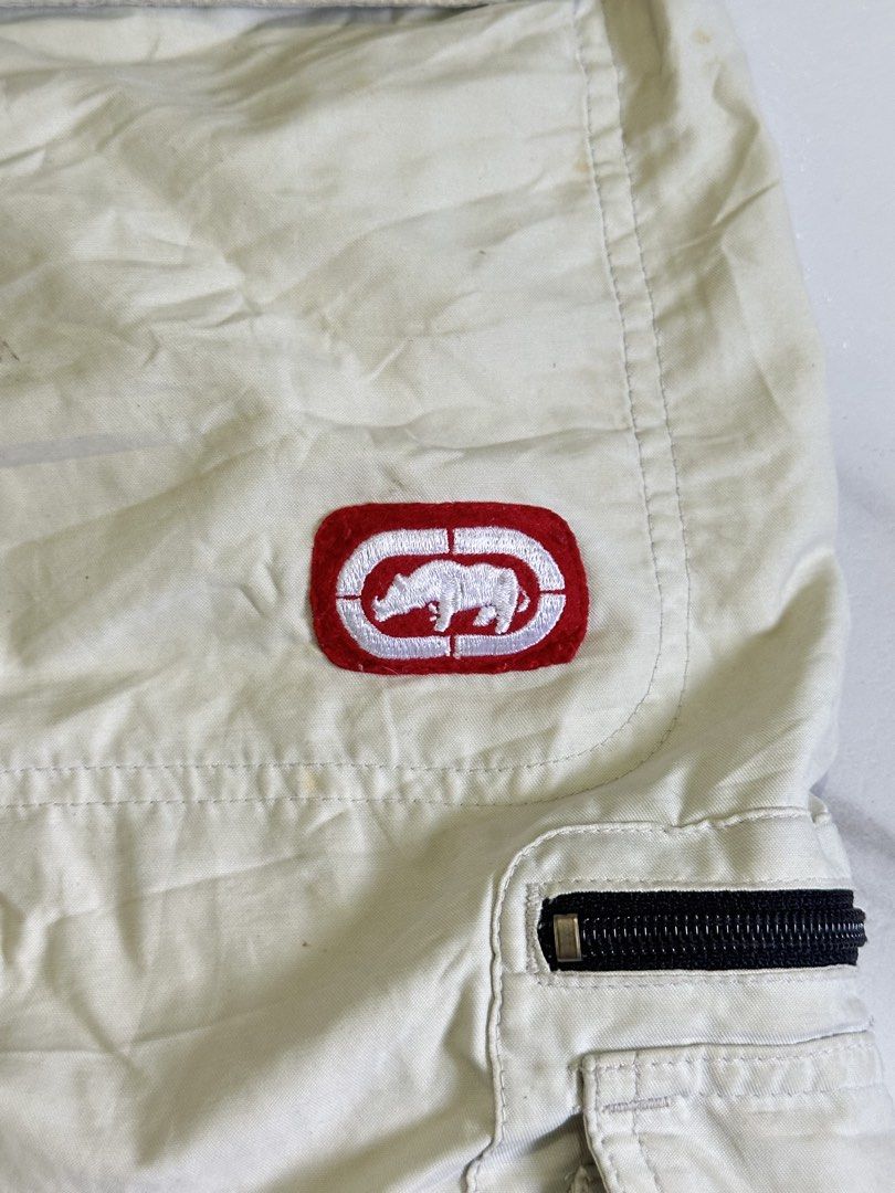 Ecko Unltd Beige Cargo Shorts with Zipper Pockets (Category: Shorts) located in Cavite. Submitted by remcadzzz (Listing ID 1469609694, Image 3). Description: - Brand: Ecko Unltd - Color: Classic beige - Material: Sturdy, durable cotton fabric - Pockets: Multiple utility pockets with secure zipper closures and red logo tag - Details: Signature rhino embroidery on the back pocket, waistband with belt loops - Style: Streetwear staple, versatile and 