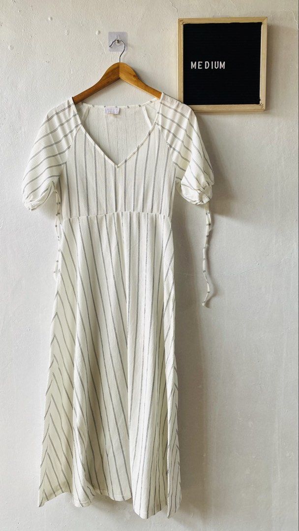 Edit Collection White Black Stripe V-Neck Dress (Category: Dresses) located in Caloocan City. Submitted by lovemyclothes21 (Listing ID 1469615892, Image 1). Description: - Style: White midi dress with vertical black stripes - Details: V-neckline, short puff sleeves with tie cuffs, fitted bodice, and flared skirt - Fabric: Lightweight, textured material - Size: Medium (tag attached) - Condition: Brand new / Excellent - Best for: Casual outings and