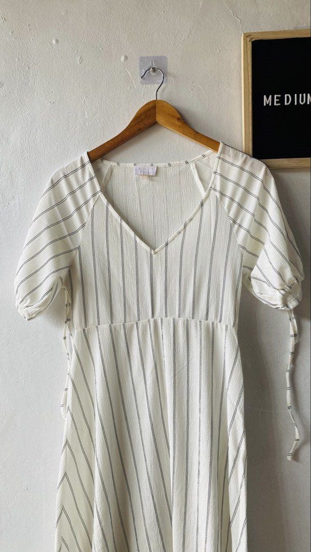 Edit Collection White Black Stripe V-Neck Dress (Category: Dresses) located in Caloocan City. Submitted by lovemyclothes21 (Listing ID 1469615892, Image 2). Description: - Style: White midi dress with vertical black stripes - Details: V-neckline, short puff sleeves with tie cuffs, fitted bodice, and flared skirt - Fabric: Lightweight, textured material - Size: Medium (tag attached) - Condition: Brand new / Excellent - Best for: Casual outings and