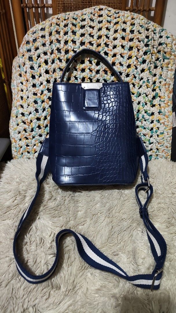 Esquire Blue Crocodile Print Handbag/sling bag (Category: Shoulder Bags) located in Cebu City. Submitted by lumaynojes00490 (Listing ID 1469671406, Image 3). Description: - Color: Dark blue with a glossy finish - Design: Mixed crocodile-embossed and smooth leather texture - Hardware: Silver-tone with a secure clasp detail - Straps: Short top handle + adjustable navy and white striped canvas strap - Capacity: Spacious interior, perfect for everyda