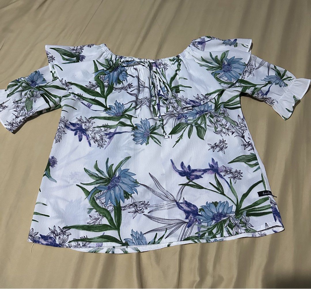 Floral Print Off-Shoulder Ruffle Top (Category: Blouses) located in Bulacan. Submitted by mithi09 (Listing ID 1469690723, Image 1). Description: - Style: Off-shoulder blouse with cute tie strings - Pattern: White with blue flowers and green leaves - Details: Ruffled neckline and half sleeves with ruffle hems - Fabric: Lightweight and breathable, ideal for PH weather - Condition: Wardrobe clear-out, hardly worn - Easy to pair: Looks great with sho