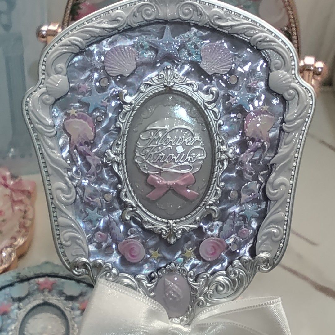 Flower Knows shell jewel handheld mirror - White pearl (Category: Mirrors) located in Manila. Submitted by rosarionav48057 (Listing ID 1469712724, Image 1). Description: - Brand: Flower Knows (shell jewel) - Item: Handheld makeup mirror with real glass surface and intricate central cameo - Design: Ornate silver frame featuring pastel purple and pink details, seashell motifs, and jellyfish designs - Feature: Elegant white satin ribbon tied at the 