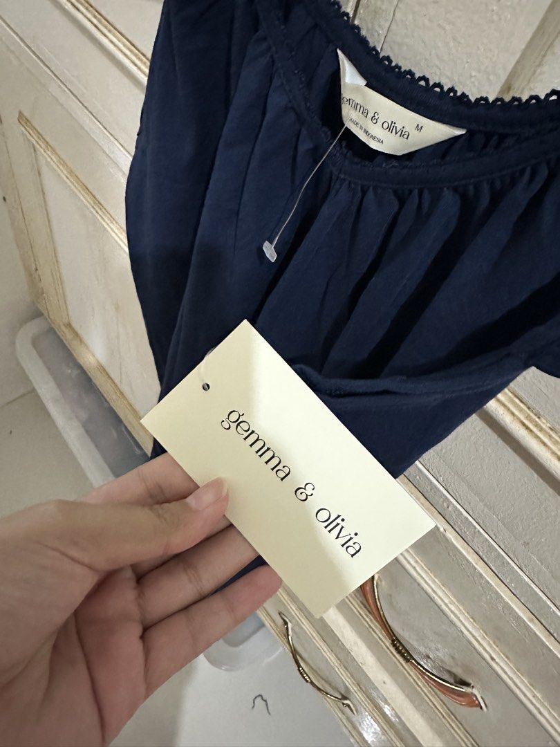 Gemma & Olivia Navy Blue Ruffle Top Size M (Category: Blouses) located in Bugallon. Submitted by lavenderlane (Listing ID 1469710120, Image 3). Description: - Brand: Gemma & Olivia - Size: Medium - Color: Dark Navy Blue - Condition: Brand new with original tags attached - Design: Off-shoulder with cute flutter sleeves, gathered front pleats, and scallop trim neckline - Material: Lightweight and comfortable - Versatility: Easy to pair with jeans o