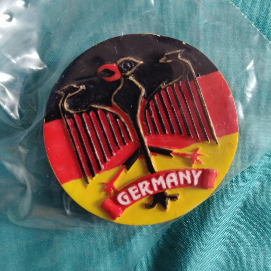 Germany Badge Pin with Eagle Design (Category: Brooches) located in Las Pinas. Submitted by chaerful8 (Listing ID 1469580292, Image 1). Description: - Round German novelty badge - Features national eagle emblem with red, black, and yellow color blocking - "GERMANY" stamped clearly on a red banner - Brand new and still sealed in clear protective plastic - Great collectible piece and souvenir for pin enthusiasts.