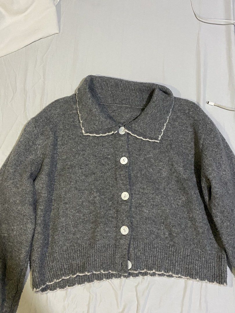 Grey knitted button-up cardigan with collar (Category: Coats, Jackets and Outerwear) located in Bulacan. Submitted by nonu_sells (Listing ID 1469686708, Image 1). Description: - Colour: Grey with white trim - Style: Long sleeves, front buttons, lapel collar - Fit: Relaxed, slightly cropped - Material: Soft and comfortable knit - Versatility: Easy to layer over basic tops and matches most bottoms.