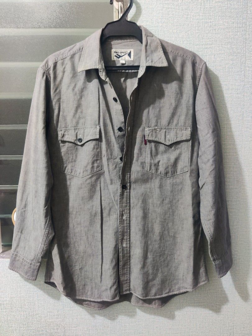 Grey Long Sleeve Shirt (Category: Tshirts & Polo Shirts ) located in Pasig City. Submitted by shiyenaaa (Listing ID 1469672007, Image 1). Description: - Brand: Pro Specs - Style: Long sleeve button-down shirt with classic collar - Color: Grey - Size: 45 - Details: Two chest pockets, one with a small red brand tab, and dark front buttons - Condition: Great casual piece for everyday wear.