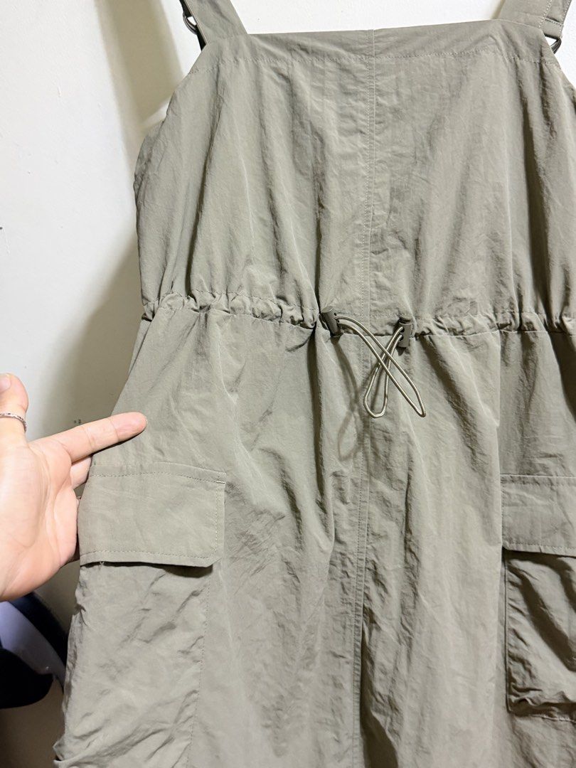 GU Olive Green Cargo Jumper Size L (Category: Jumpsuits) located in Paete. Submitted by skydruemadison (Listing ID 1469696500, Image 2). Description: - Brand: GU - Color: Olive Green - Size: Large - Style: Sleeveless utility jumper with square neckline and midi length - Material: Lightweight nylon - Features: Adjustable drawstring waist for a cinched fit and practical side cargo pockets on the skirt - Condition: Easy slip-on piece, perfect for ca