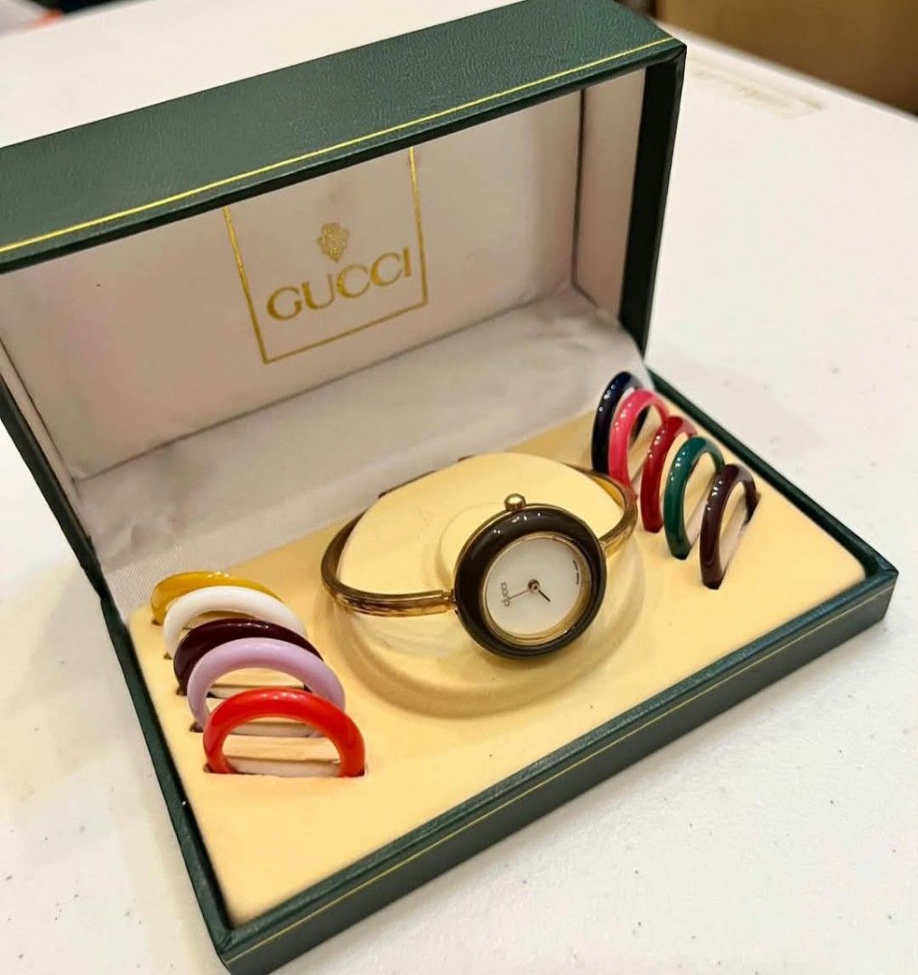 Gucci Change Bezel Bangle Watch with Box (Category: Luxury Watches) located in Malolos. Submitted by lizarondoe59660 (Listing ID 1469572973, Image 2). Description: - Authentic vintage Gucci bangle watch - Gold-tone bracelet with 10 interchangeable colored bezels (brown currently attached, plus red, white, yellow, purple, dark blue, pink, burgundy, green, and dark brown) - Includes original dark green Gucci presentation box with gold logo - Timele