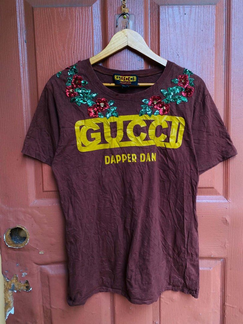 Gucci Dapper Dan Brown T-Shirt with Sequin Flowers (Category: Shirts) located in Digos. Submitted by thrifthed.ph (Listing ID 1469655003, Image 1). Description: - Authentic Gucci x Dapper Dan brown t-shirt -large -dimes:20.5/28 -like new -cl:10/10 -color may vary due to sun-light -need wash -authentic -solid condi -solid colorate -need wash - Bold yellow logo across the chest - Detailed red and green sequin flower embroidery along the neckline - 