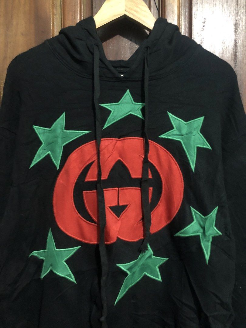 Gucci Interlocking G Star Patch Black Hoodie (Category: Coats, Jackets and Outerwear) located in Quezon City. Submitted by yeahsource222 (Listing ID 1469745172, Image 2). Description: - Brand: Gucci - Color: Black with red interlocking G logo and green star patches - Size: Medium (M) - Material: 100% Cotton - Origin: Made in Italy - Features: Drawstring hood, ribbed cuffs and hem, relaxed fit - Condition: Excellent, well-maintained - Mode of tran
