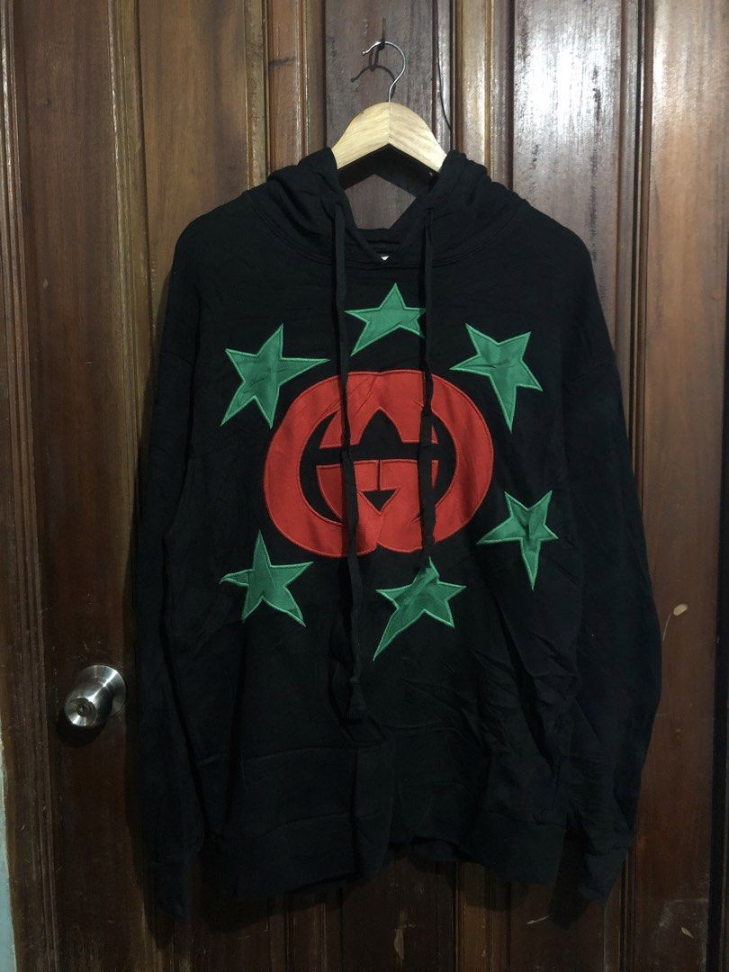 Gucci Interlocking G Star Patch Black Hoodie (Category: Coats, Jackets and Outerwear) located in Quezon City. Submitted by yeahsource222 (Listing ID 1469745172, Image 1). Description: - Brand: Gucci - Color: Black with red interlocking G logo and green star patches - Size: Medium (M) - Material: 100% Cotton - Origin: Made in Italy - Features: Drawstring hood, ribbed cuffs and hem, relaxed fit - Condition: Excellent, well-maintained - Mode of tran