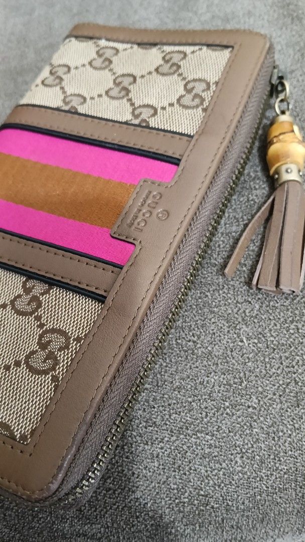 Gucci Rania Canvas Zip Around Wallet (Category: Luxury Bags & Wallets) located in Cebu City. Submitted by mcmapio (Listing ID 1469602346, Image 2). Description: - Authentic Gucci zip-around wallet - Brown monogram canvas with chic pink and tan center stripes - Unique bamboo tassel zipper pull - Organized interior with multiple card slots, slip pockets, and a zippered coin compartment - Serial number stamped inside for authenticity verification.