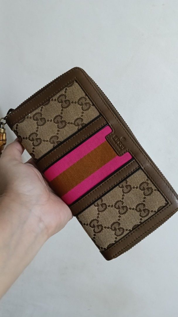 Gucci Rania Canvas Zip Around Wallet (Category: Luxury Bags & Wallets) located in Cebu City. Submitted by mcmapio (Listing ID 1469602346, Image 1). Description: - Authentic Gucci zip-around wallet - Brown monogram canvas with chic pink and tan center stripes - Unique bamboo tassel zipper pull - Organized interior with multiple card slots, slip pockets, and a zippered coin compartment - Serial number stamped inside for authenticity verification.