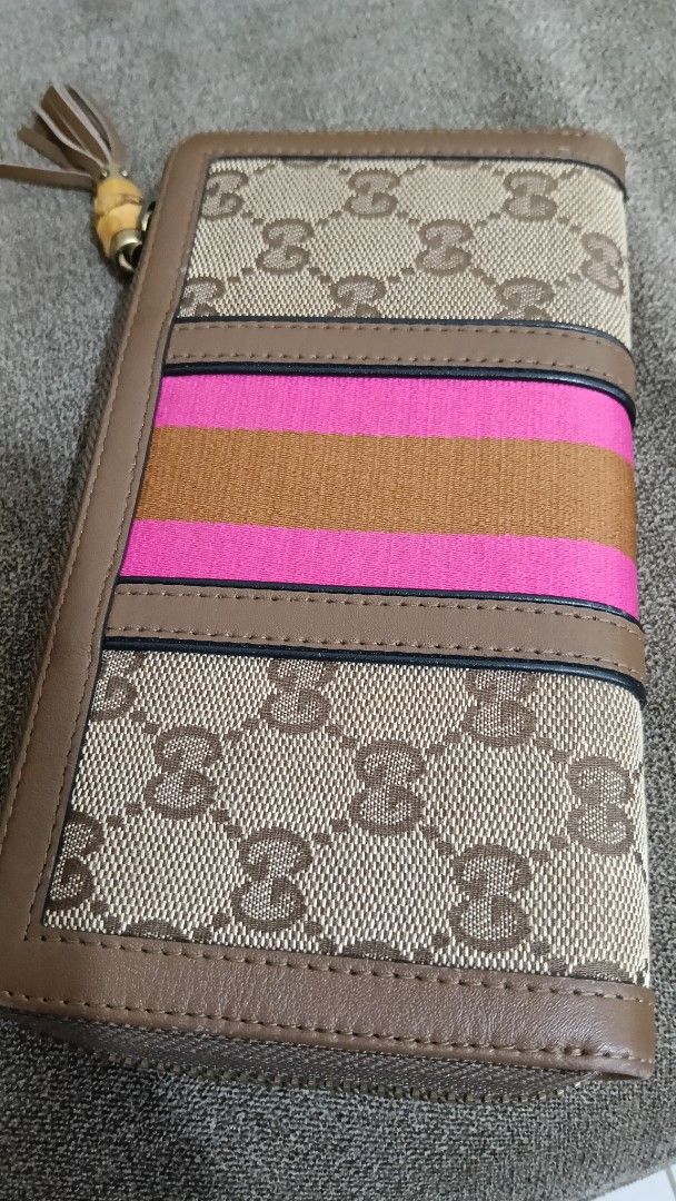 Gucci Rania Canvas Zip Around Wallet (Category: Luxury Bags & Wallets) located in Cebu City. Submitted by mcmapio (Listing ID 1469602346, Image 3). Description: - Authentic Gucci zip-around wallet - Brown monogram canvas with chic pink and tan center stripes - Unique bamboo tassel zipper pull - Organized interior with multiple card slots, slip pockets, and a zippered coin compartment - Serial number stamped inside for authenticity verification.