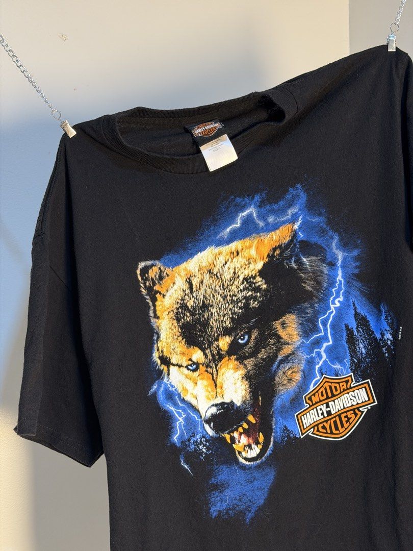 Harley Davidson Wolf Thunder (Category: Tshirts & Polo Shirts ) located in Manila. Submitted by sugbo_vntg (Listing ID 1469745735, Image 2). Description: Harley-Davidson “Wolf Thunder” ⚡🐺 A snarling wolf with icy blue eyes, caught in a lightning storm over a dark pine forest. This is a Florida dealer tee featuring the Sunshine Skyway Bridge, palm trees, and a Gulf Coast sunset. Size: L | 21 x 28.5 Available🔥.
