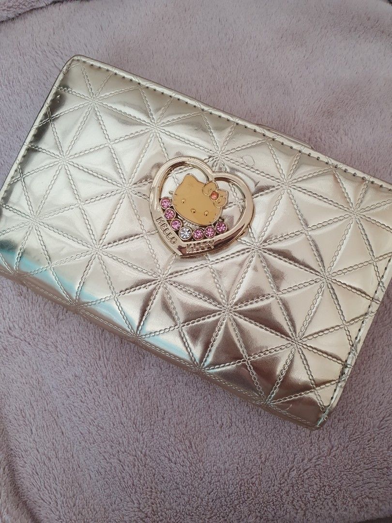 Hello Kitty Gold Quilted Wallet (Category: Wallets & Card holders) located in Marilao. Submitted by majoriety (Listing ID 1469596920, Image 1). Description: - Gorgeous gold metallic wallet with trendy geometric quilting - Features an adorable Kitty heart charm with pink rhinestone accents - Secure snap closure keeps your cash and cards safe - Compact size fits easily into small bags and pockets - Fun and stylish accessory for Sanrio and Kitty fan