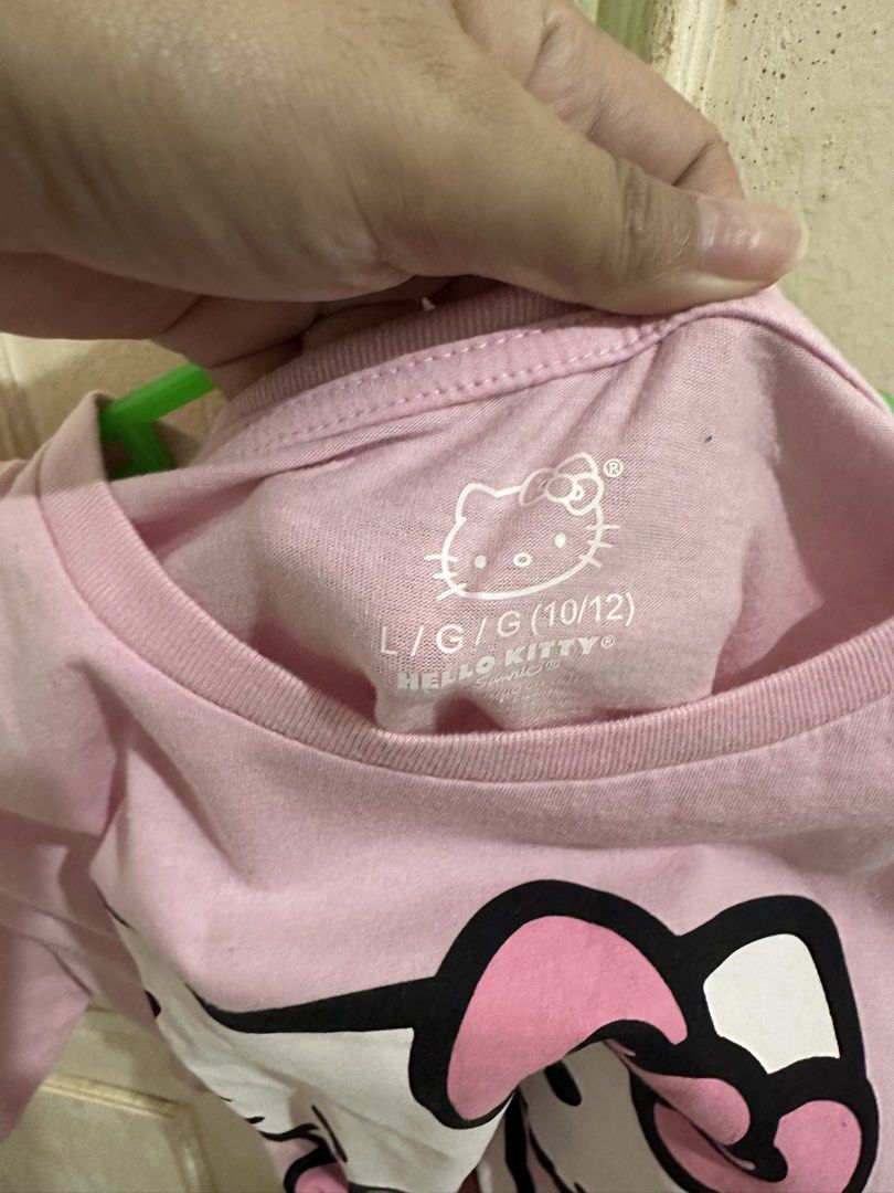 Hello Kitty Pink T-Shirt Size L 10/12 (Category: Shirts) located in Bugallon. Submitted by lavenderlane (Listing ID 1469702949, Image 2). Description: - Design: Big Kitty graphic holding an apple on the front - Color: Light pink - Size: L (10/12) tag (kid’s size) - Material: Soft and comfortable cotton - Style: Short sleeves, round neckline, perfect for casual daily wear and Sanrio fans.