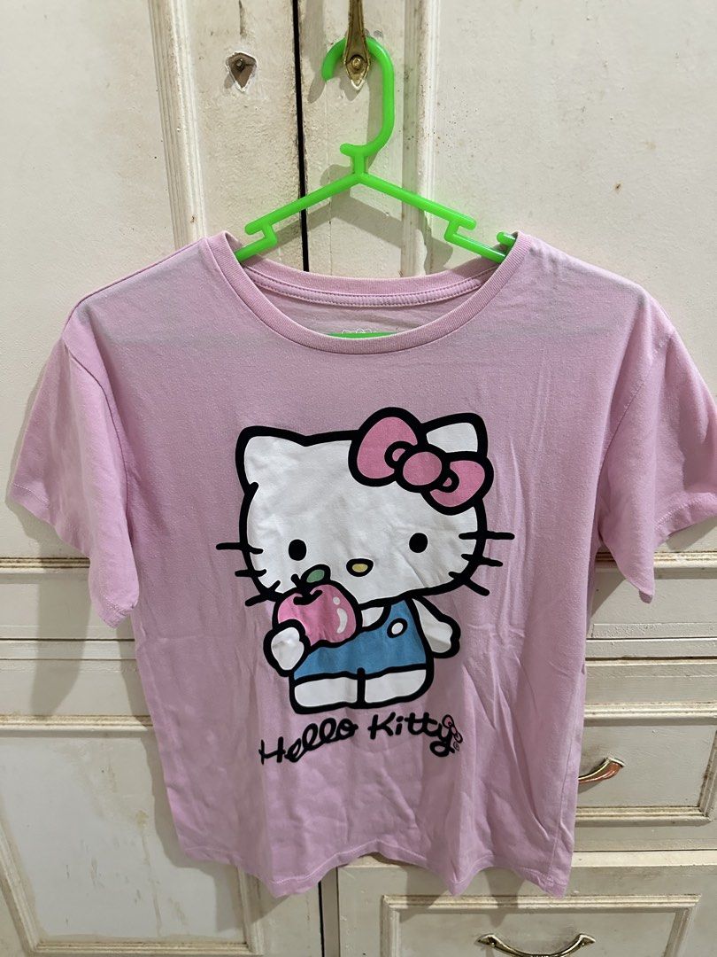 Hello Kitty Pink T-Shirt Size L 10/12 (Category: Shirts) located in Bugallon. Submitted by lavenderlane (Listing ID 1469702949, Image 1). Description: - Design: Big Kitty graphic holding an apple on the front - Color: Light pink - Size: L (10/12) tag (kid’s size) - Material: Soft and comfortable cotton - Style: Short sleeves, round neckline, perfect for casual daily wear and Sanrio fans.