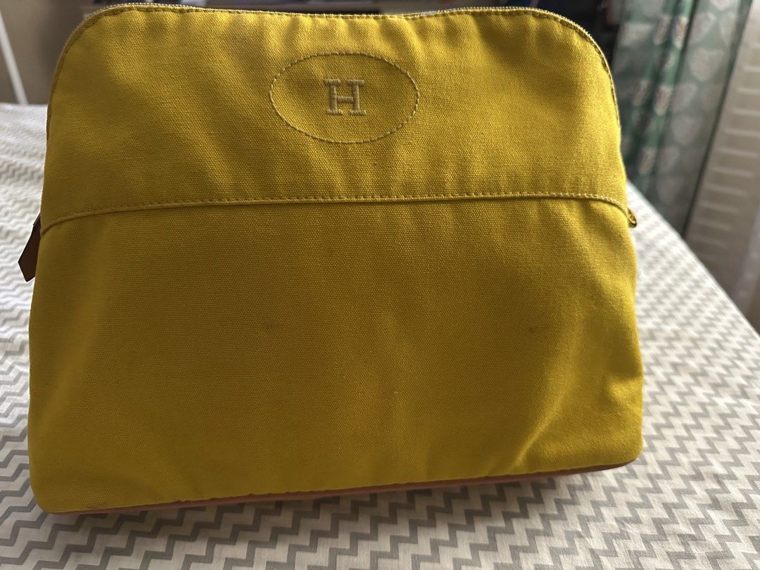 Hermès Yellow Canvas Pouch (Category: Purses & Pouches) located in Antipolo. Submitted by prelovedcloseta (Listing ID 1469609607, Image 1). Description: - Color: Bright yellow canvas with brown leather base trim - Design: Embroidered H logo inside an oval on the front - Closure: Zipper closure with a convenient leather pull tab - Interior: Clean fabric inside and out, structured shape to keep items organized - Condition: Excellent, well-maintaine